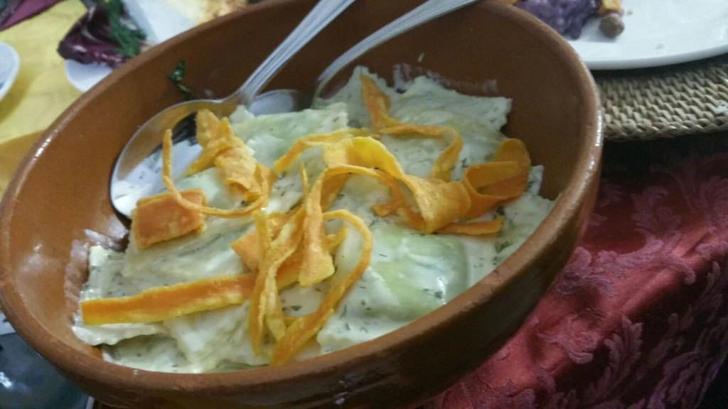 Ravioli ripiedi di spinaci, ricoperti di panna e zucca fritta