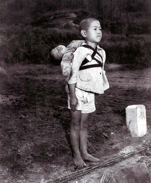 bambino di Nagasaki con il fratellino morto sulle spalle mentre aspetta per la cremazione